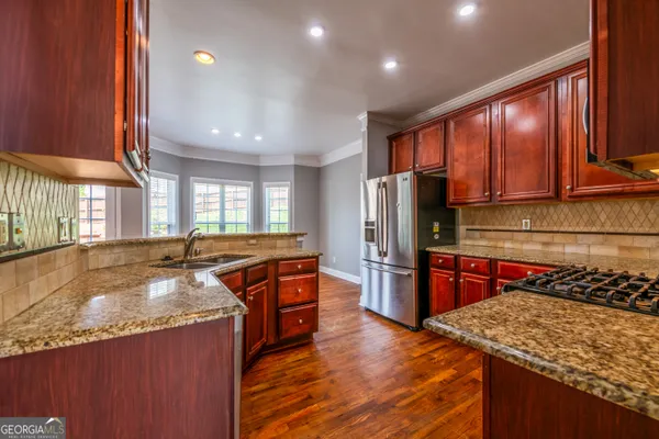 a kitchen with stainless steel appliances granite countertop wooden cabinets a stove and a sink