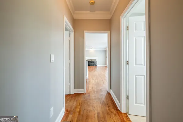 a view of a hallway with wooden floor and a bathroom