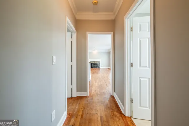 a view of a hallway with wooden floor and a bathroom