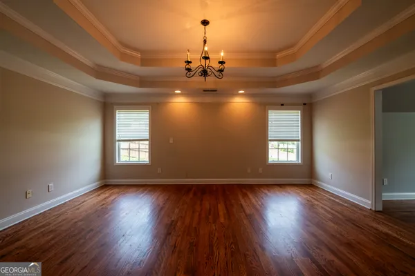 a view of a room with wooden floors chandelier and windows