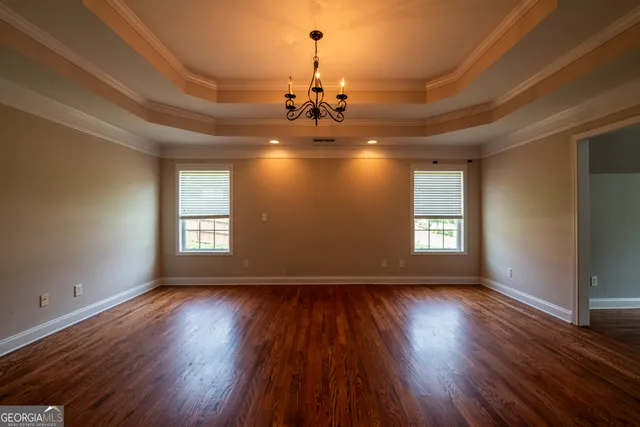 a view of a room with wooden floors chandelier and windows