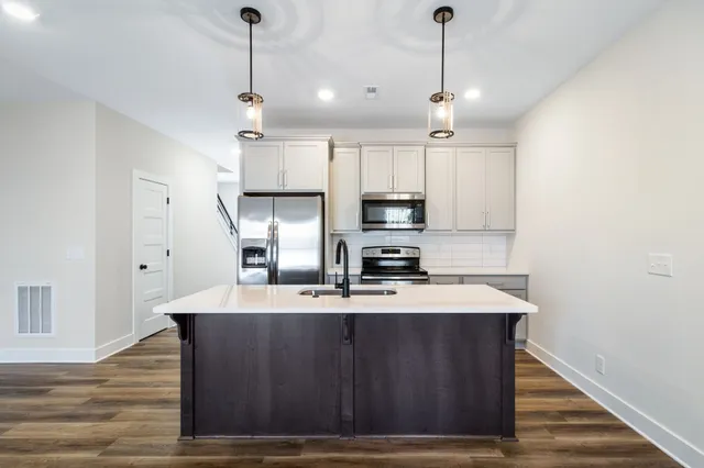 a kitchen with kitchen island granite countertop a sink cabinets and wooden floor