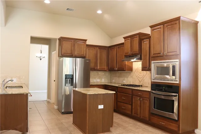 a kitchen with stainless steel appliances granite countertop a refrigerator and a stove top oven