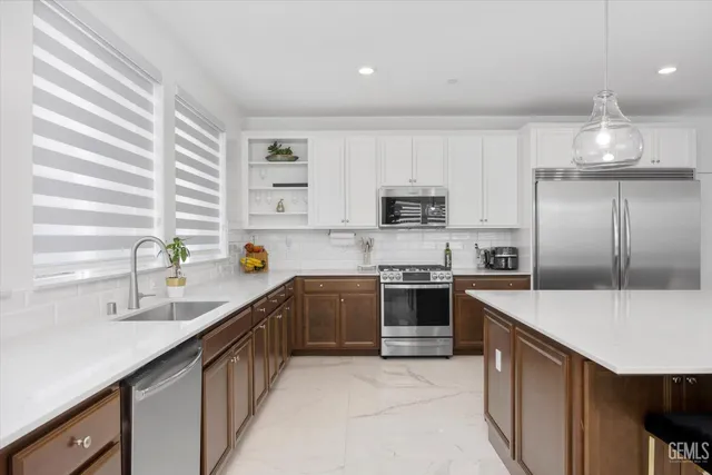 a kitchen with stainless steel appliances a sink dishwasher a stove top oven a refrigerator with island and cabinets