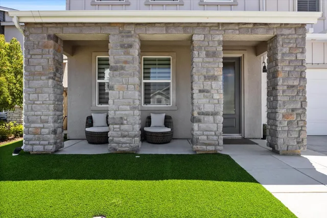 a view of a brick house with a yard potted plants and a table