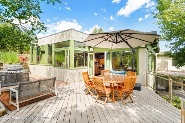 a view of a patio with table and chairs with wooden floor and fence
