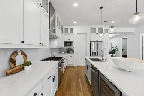 a kitchen with stainless steel appliances granite countertop a sink a stove and a wooden floors