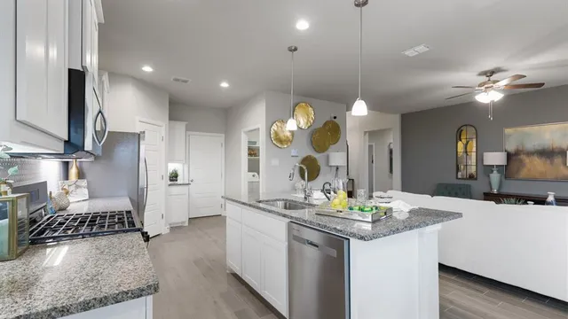 a kitchen with stainless steel appliances granite countertop a sink a stove and a wooden floors