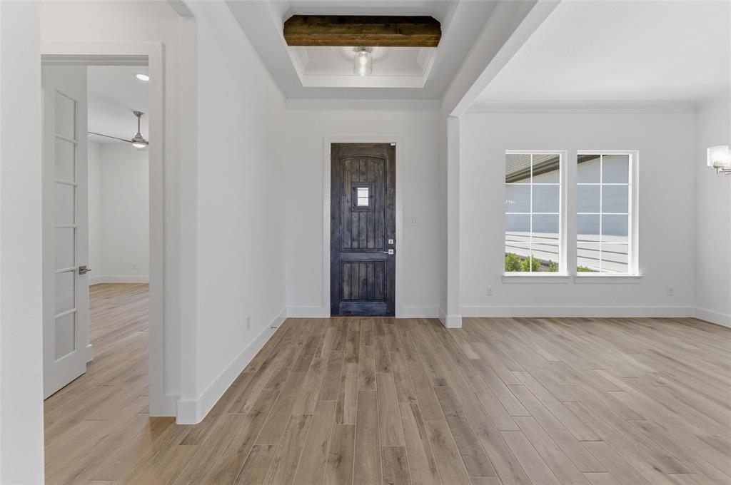 815 Vly Rdg Road Van Alstyne, TX 75495 - Photo 6 of 29 Spacious entry foyer featuring wood-finish flooring, a dark wood-paneled entry door with frosted glass, and a recessed ceiling with a substantial wood beam accent