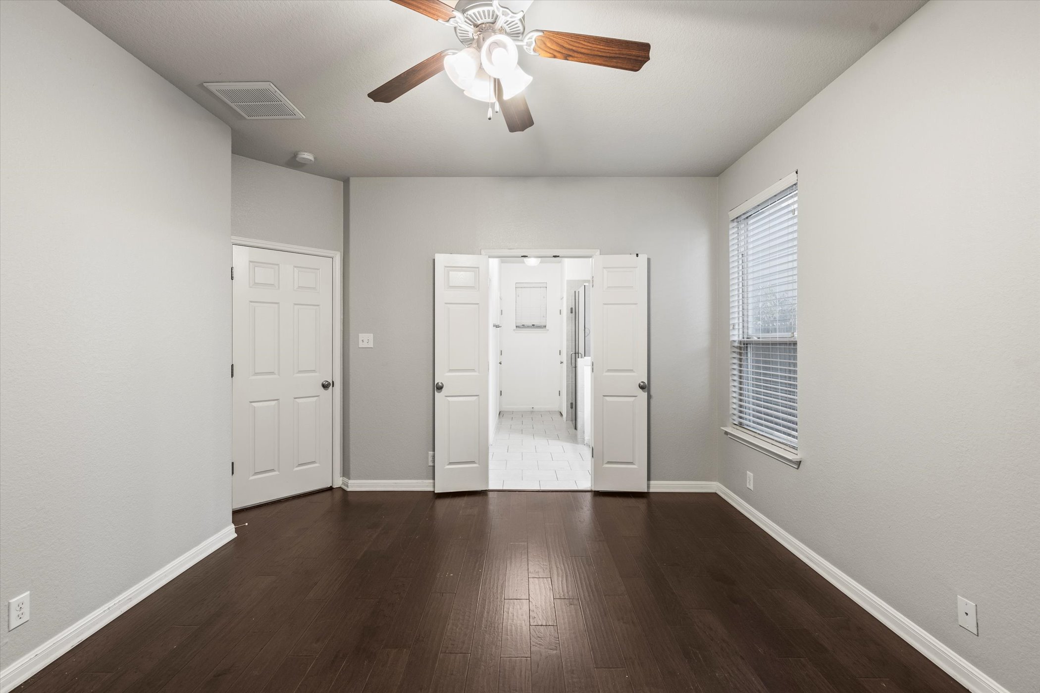 7337 Menchaca Road, Unit #22 Austin, TX 78745 - Photo 8 of 25 Primary bedroom with wood flooring, ceiling fan, and ensuite bath with walk-in closet.