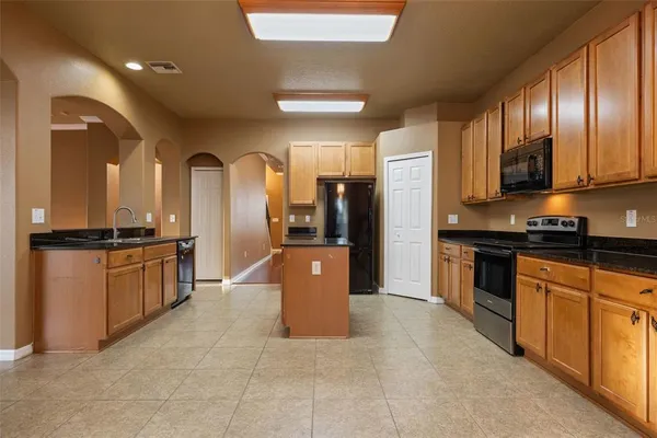 a large kitchen with stainless steel appliances kitchen island granite countertop a refrigerator a stove a sink and dishwasher