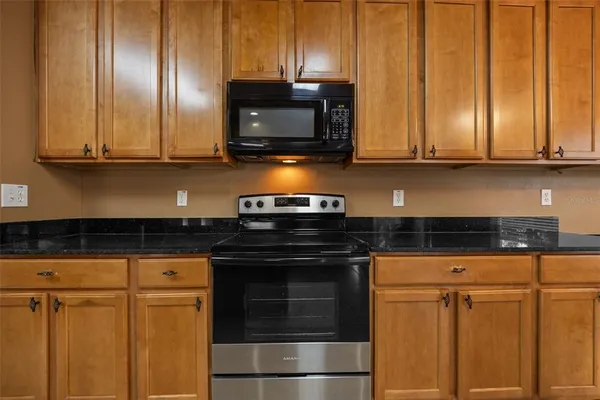 a kitchen with stainless steel appliances granite countertop a stove microwave and cabinets