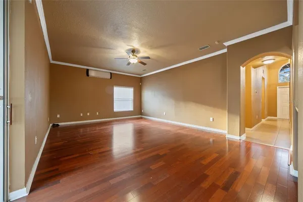 a view of an empty room with wooden floor and a window
