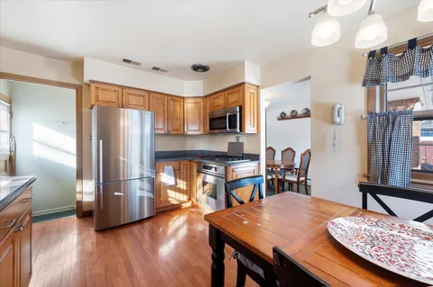 a kitchen with granite countertop a refrigerator a stove a sink dishwasher and microwave with wooden floor