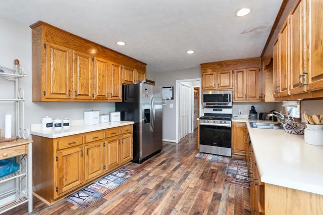a kitchen with stainless steel appliances granite countertop a refrigerator a stove top oven a sink dishwasher and wooden cabinets with wooden floor