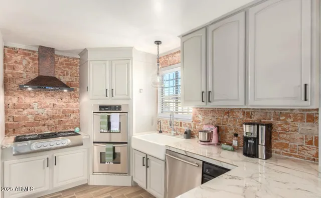 a kitchen with stainless steel appliances granite countertop a stove a sink and white cabinets
