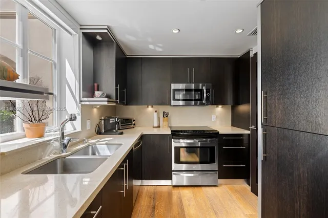 a kitchen with kitchen island granite countertop a sink stainless steel appliances and cabinets