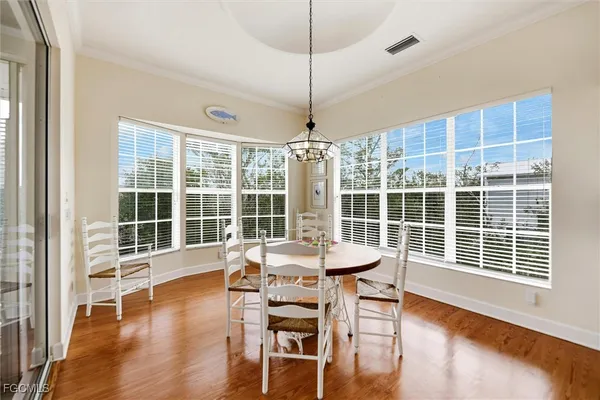a dining room with wooden floor a chandelier and windows