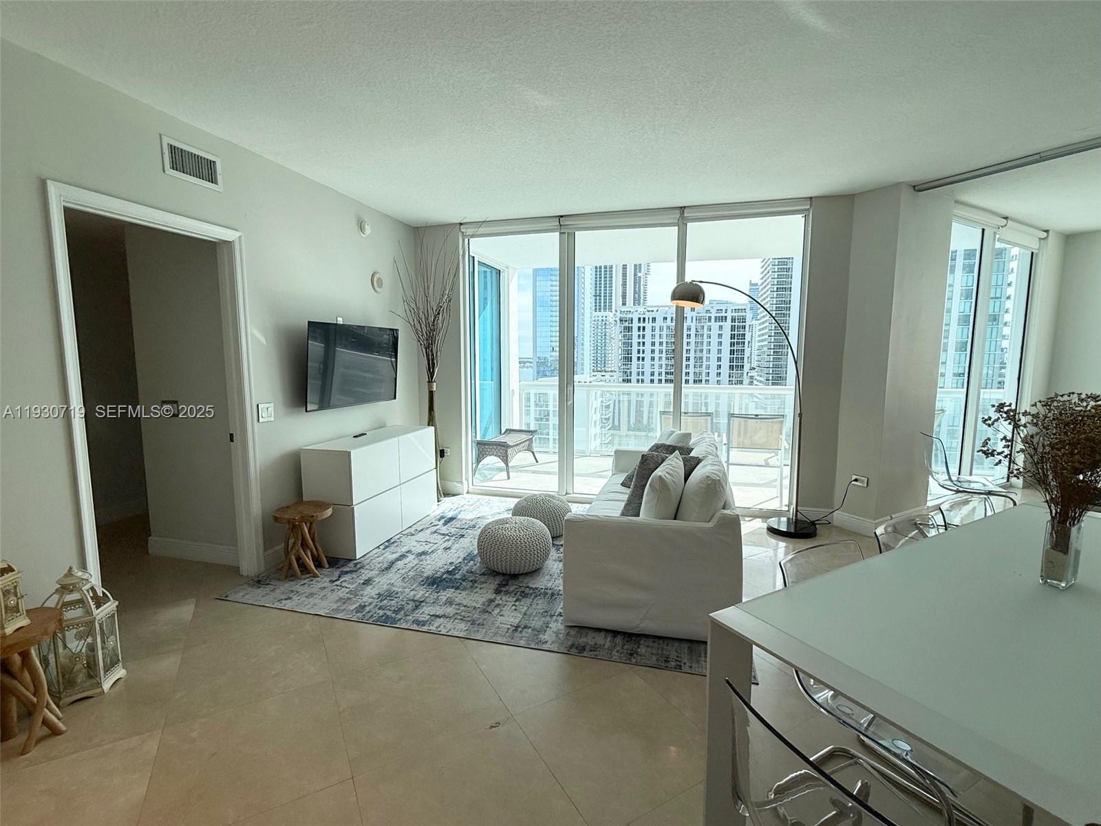 480 Northeast 30th Street, Unit 1505 Miami, FL 33137 - Photo 2 of 20 a living room with furniture and a flat screen tv