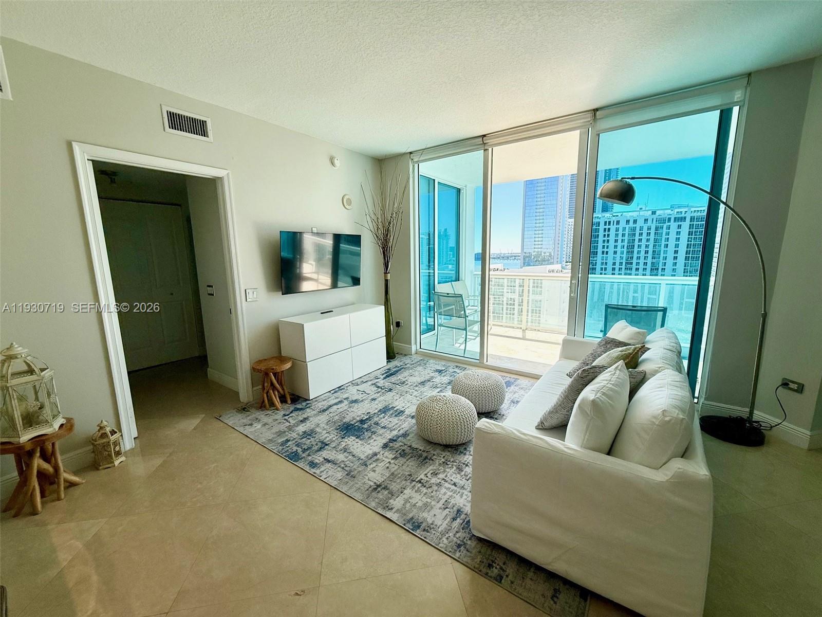 480 Northeast 30th Street, Unit 1505 Miami, FL 33137 - Photo 2 of 21 a living room with furniture and a flat screen tv
