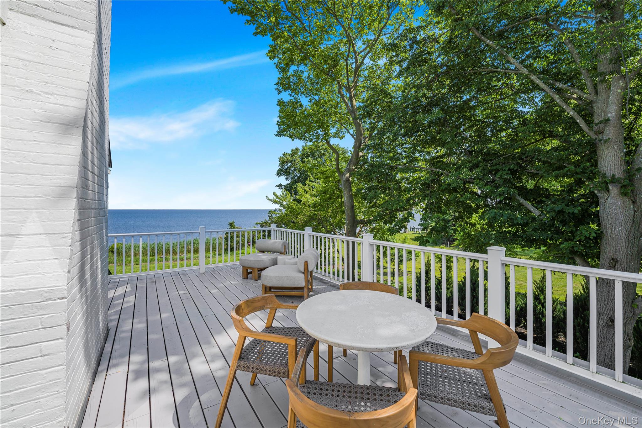 5 Thorn Hedge Road Bellport, NY 11713 - Photo 22 of 42 a view of a balcony with table and chairs with wooden floor and fence