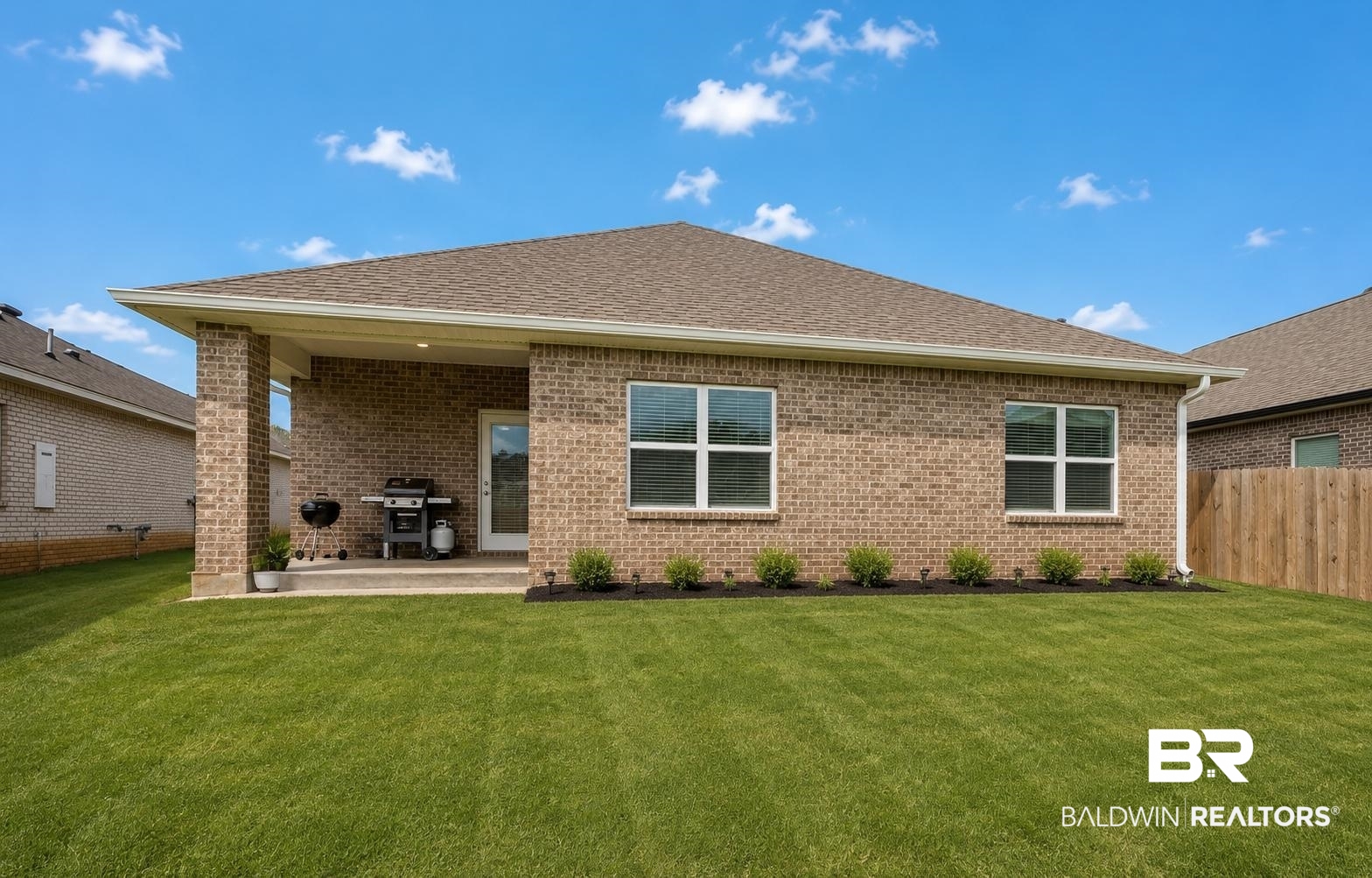 31468 Memphis Loop Daphne, AL 36527 - Photo 23 of 24 Expansive green lawn with a covered patio featuring brick columns, a concrete slab, and an exterior door with glass panels