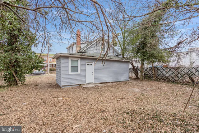 a view of a house with a large tree and wooden fence
