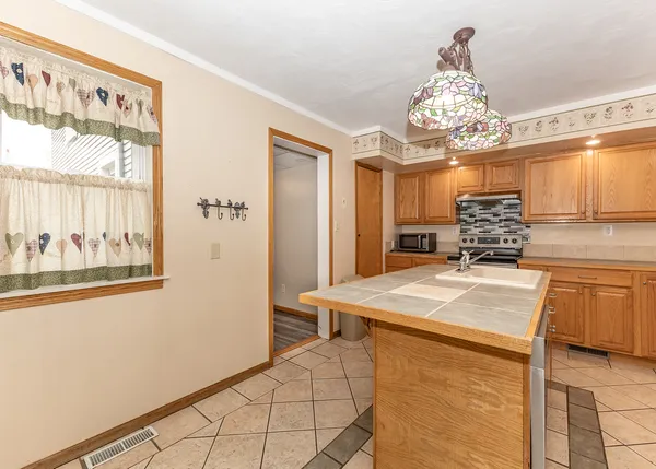 a room with stainless steel appliances kitchen island a chandelier