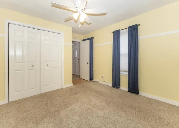 an empty room with closet and a ceiling fan