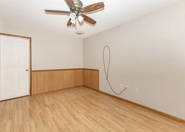 an empty room with a ceiling fan and wooden floor