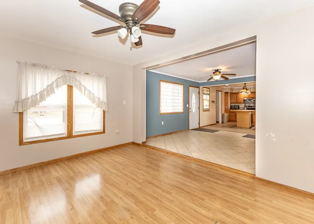 a view of an empty room with window and wooden floor