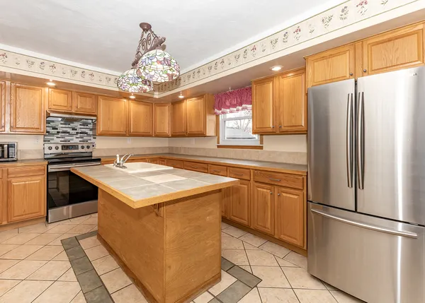 a kitchen with stainless steel appliances granite countertop a refrigerator a sink dishwasher a stove and white cabinets