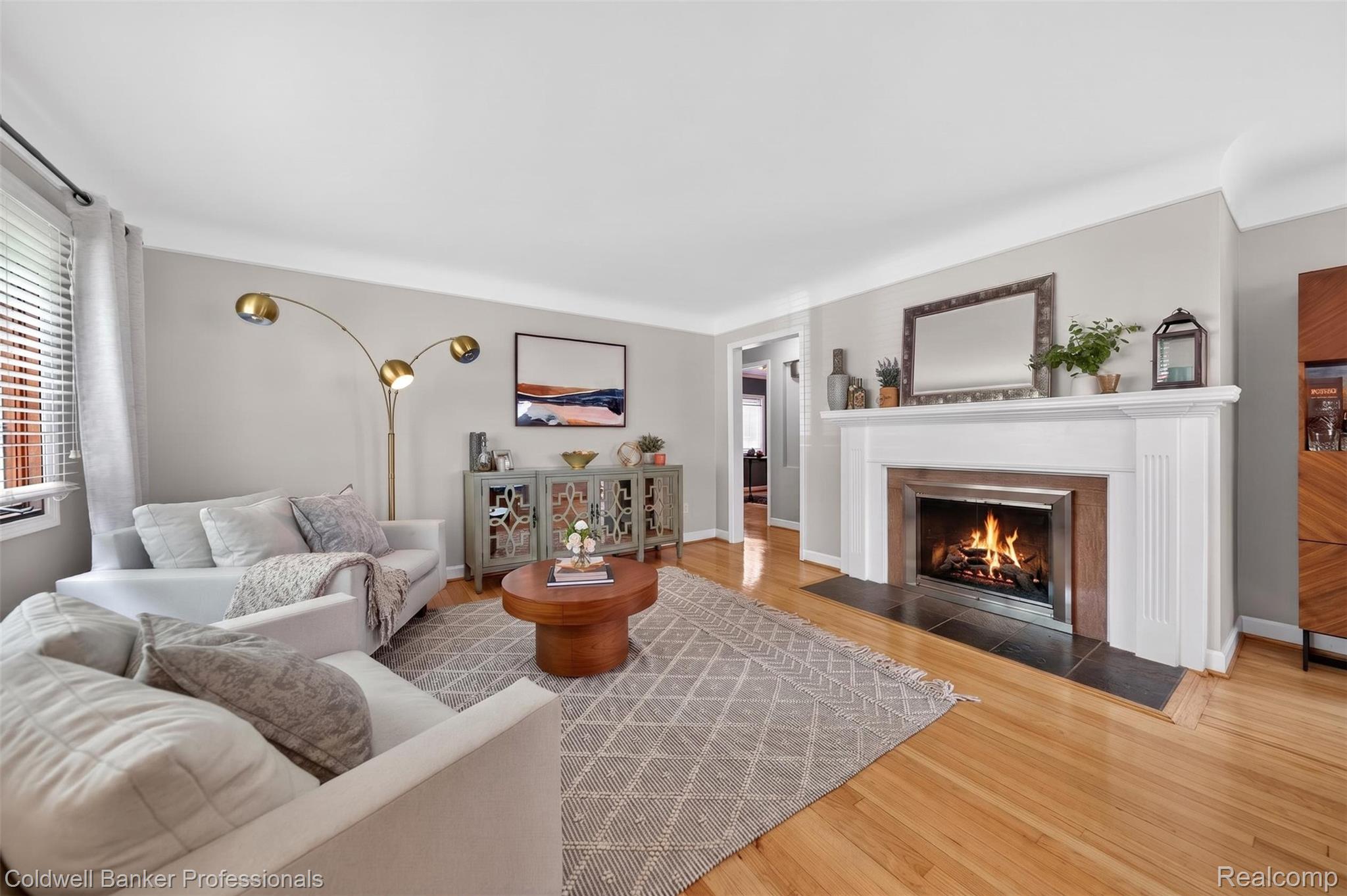 2666 Windemere Road Birmingham, MI 48009 - Photo 2 of 24 Living area featuring a white wood-mantled fireplace with a dark stone hearth, wood-finish flooring, and crown molding
