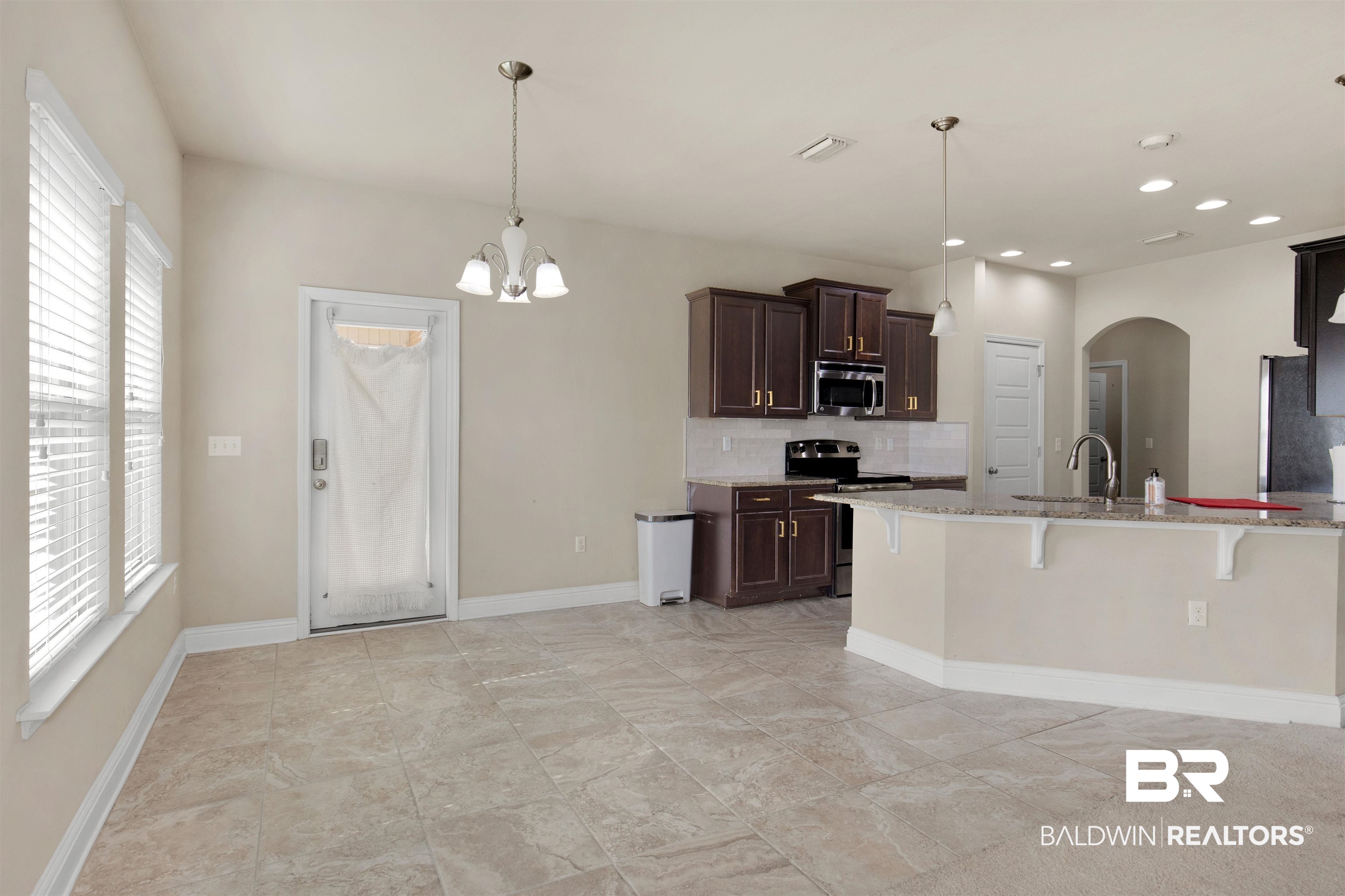 122 Open Field Drive Fairhope, AL 36532 - Photo 8 of 27 Kitchen with stainless steel appliances, pendant lighting, a breakfast bar area, light stone counters, and light tile patterned floors
