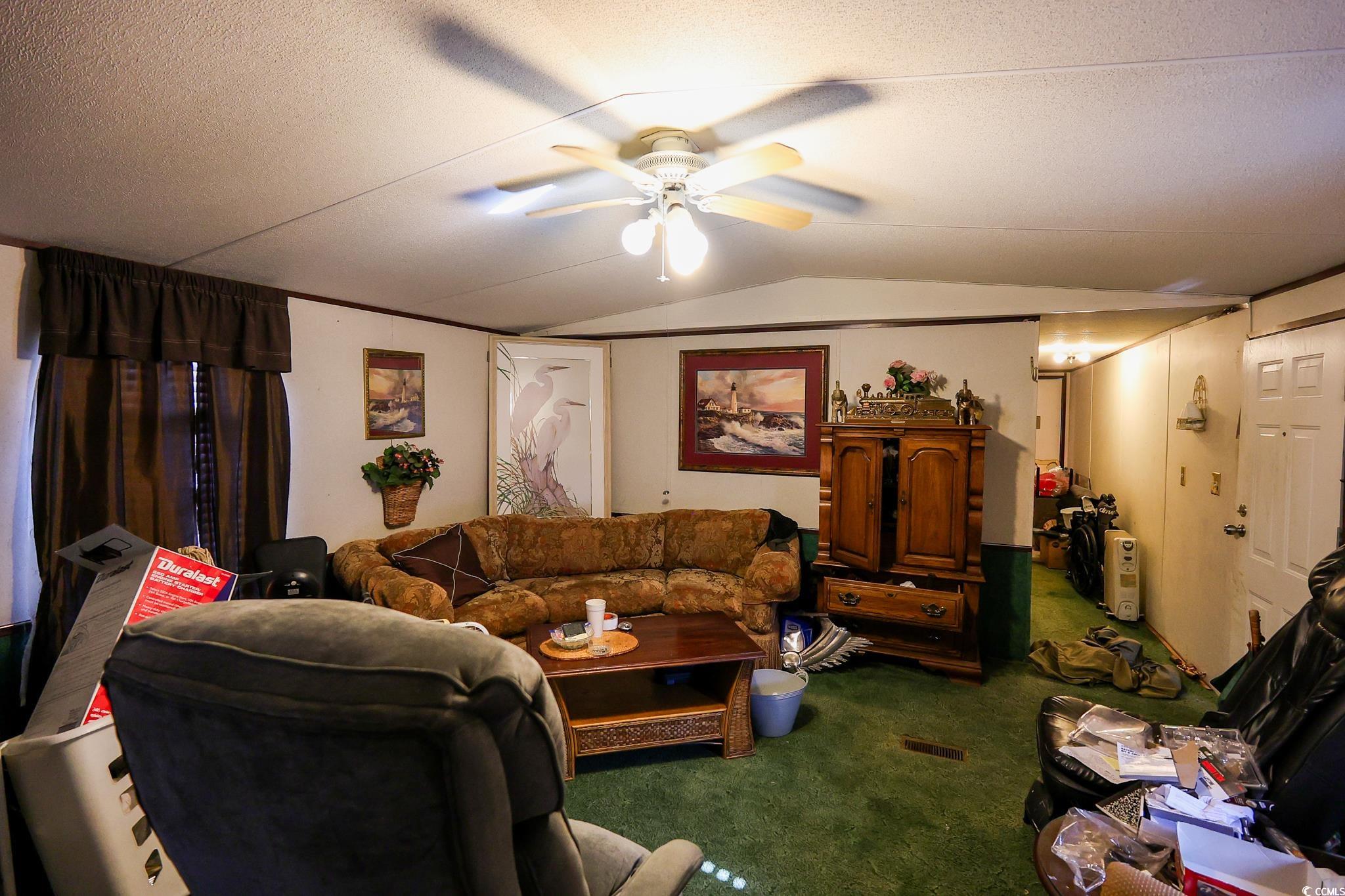 5266 Highmarket Street Georgetown, SC 29440 - Photo 4 of 17 Carpeted living room featuring ceiling fan, lofted ceiling, and a textured ceiling