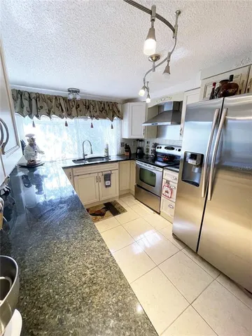 a kitchen with stainless steel appliances granite countertop a sink dishwasher stove and refrigerator