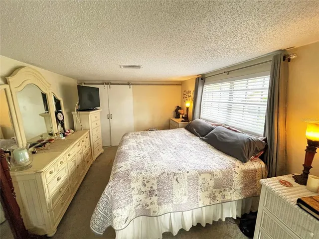 a bedroom with a bed a flat screen tv and dresser