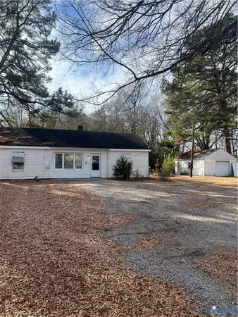 a front view of a house with a yard and a large tree