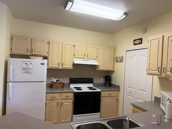 a kitchen with stainless steel appliances a refrigerator a stove a sink and white cabinets