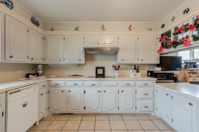 a kitchen with white cabinets and sink