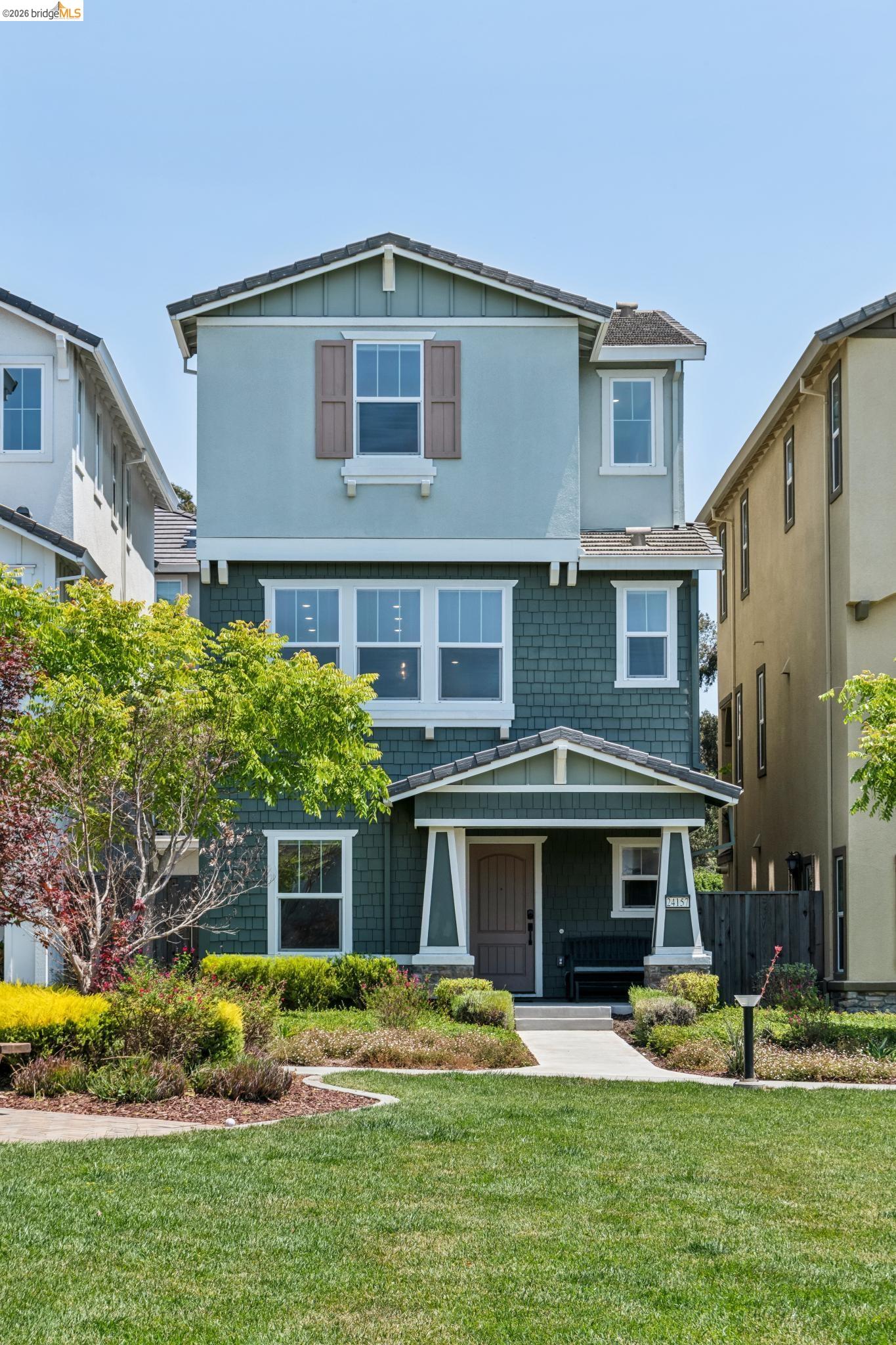 24157 Amaranth Loop Hayward, CA 94541 - Photo 2 of 63 Multi-story residence featuring a covered entry porch, two-tone exterior siding, shuttered windows, a front yard with manicured lawn, and mature landscaping