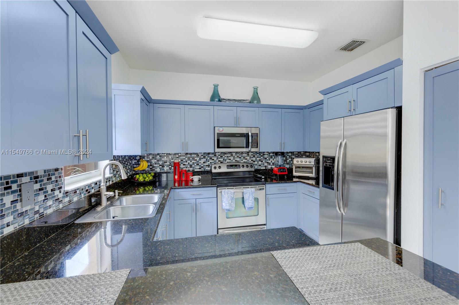 a kitchen with stainless steel appliances granite countertop a refrigerator a stove and a sink