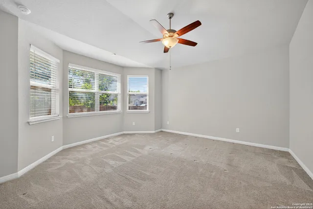 an empty room with windows and fan