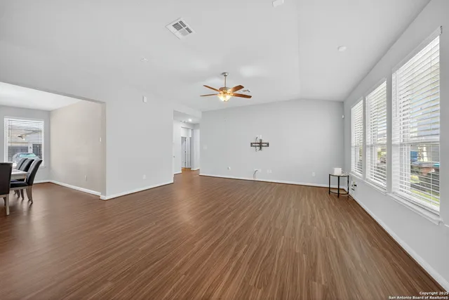 an empty room with wooden floor and windows
