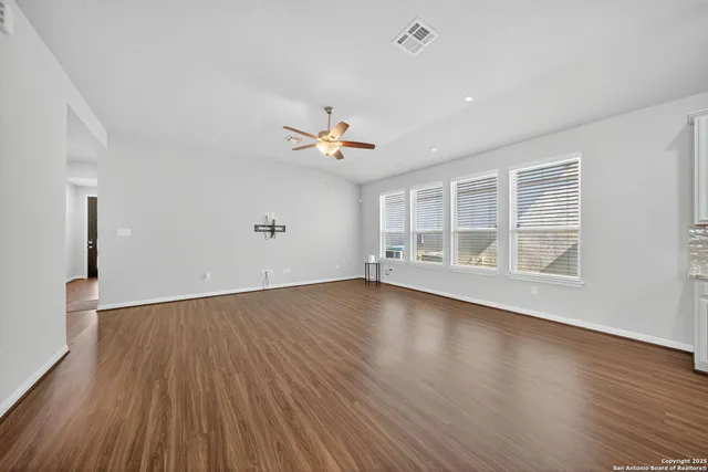 an empty room with wooden floor and windows