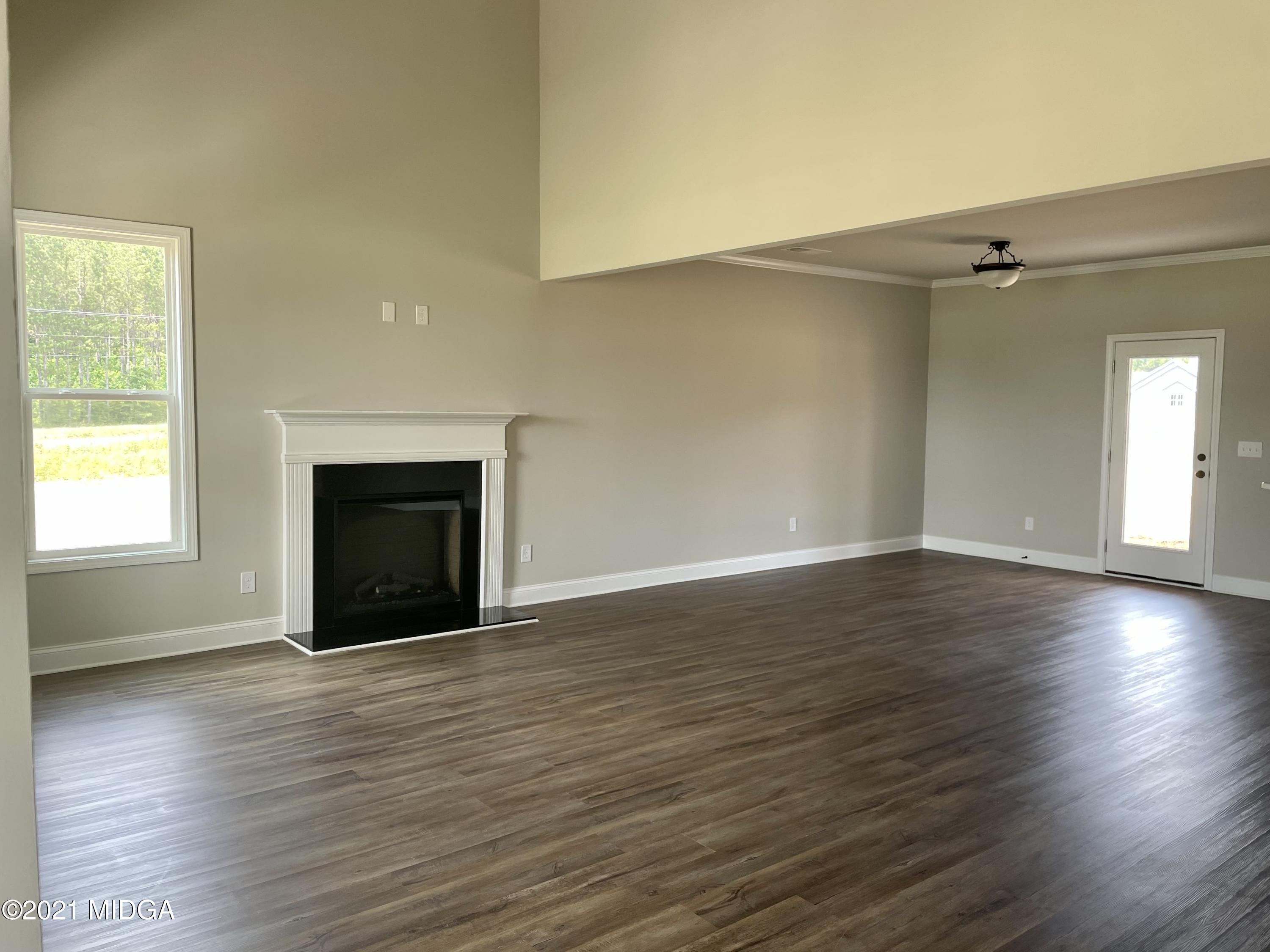 1452 Bunn Road Forsyth, GA 31029 - Photo 2 of 9 an empty room with wooden floor fireplace and windows