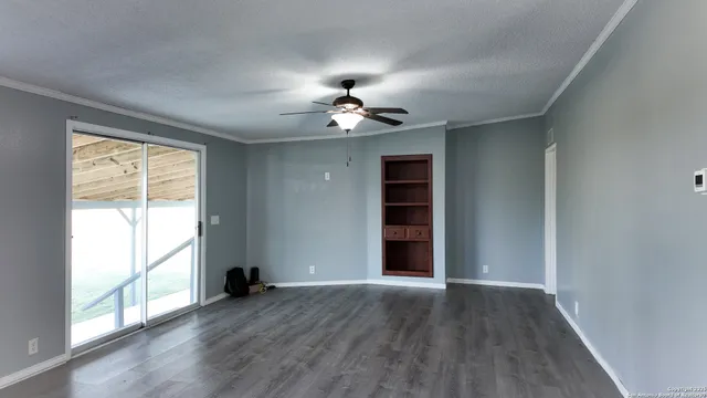 an empty room with wooden floor chandelier fan and windows