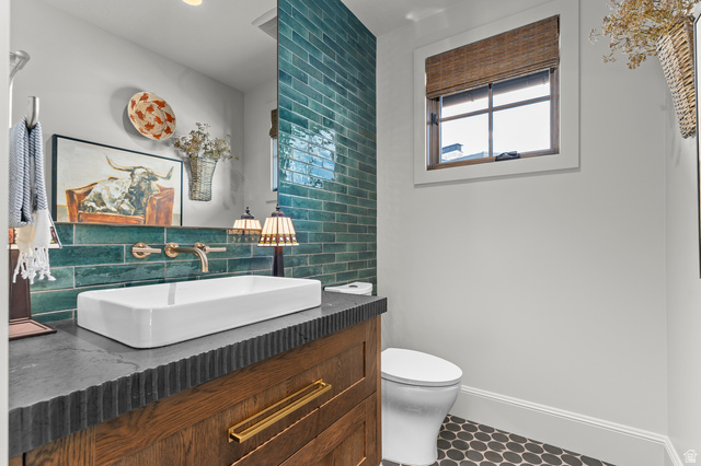 2192 East Outlaw Road Kamas, UT 84036 - Photo 45 of 80 Rectangular vessel sink with wall-mounted brass faucet, wood vanity with textured countertop, teal subway tile accent wall, and hexagonal floor tiles