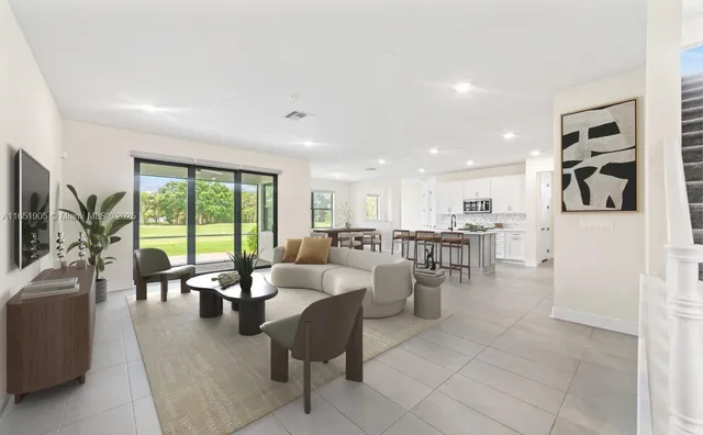 a room with lots of white furniture wooden floor and a large window