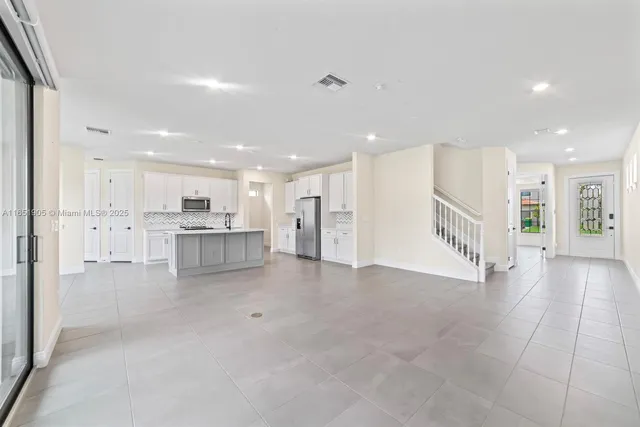 a view of kitchen with refrigerator and white cabinets